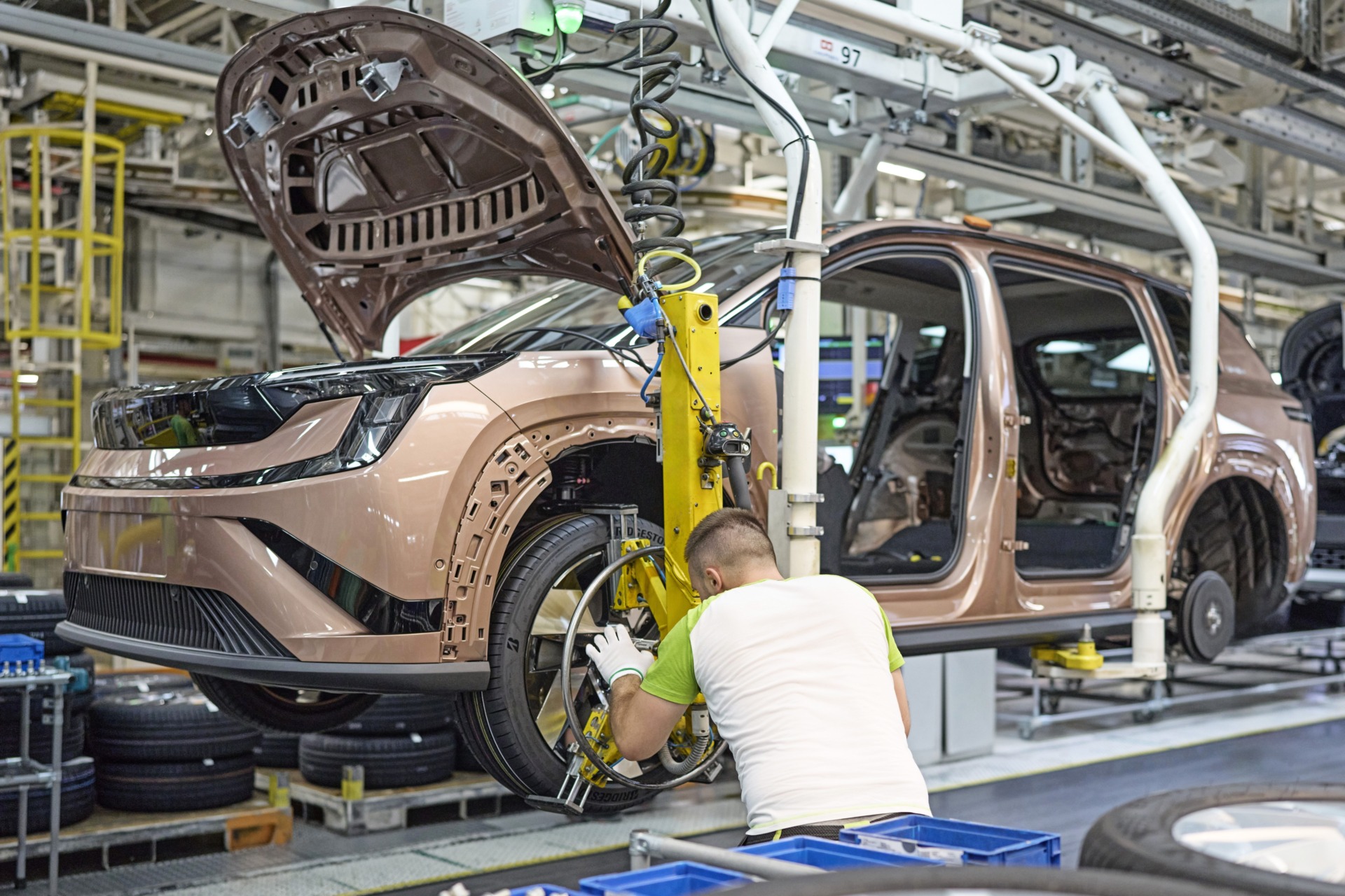 Autoproduktion: Mitarbeiter montiert Rad an neuem Elektroauto in Fabrik