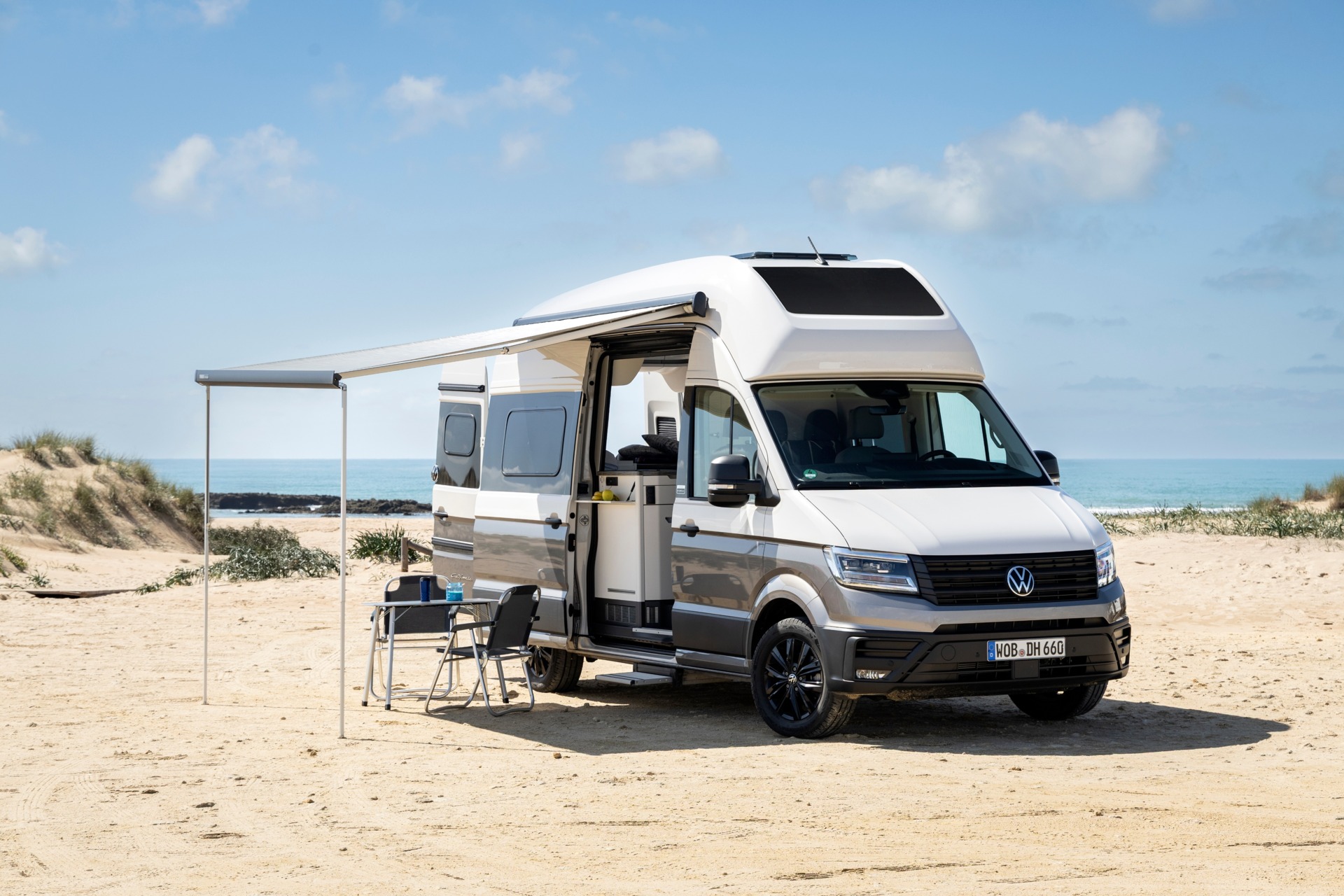 Wohnmobil mit ausgefahrener Markise am Strand vor dem Meer