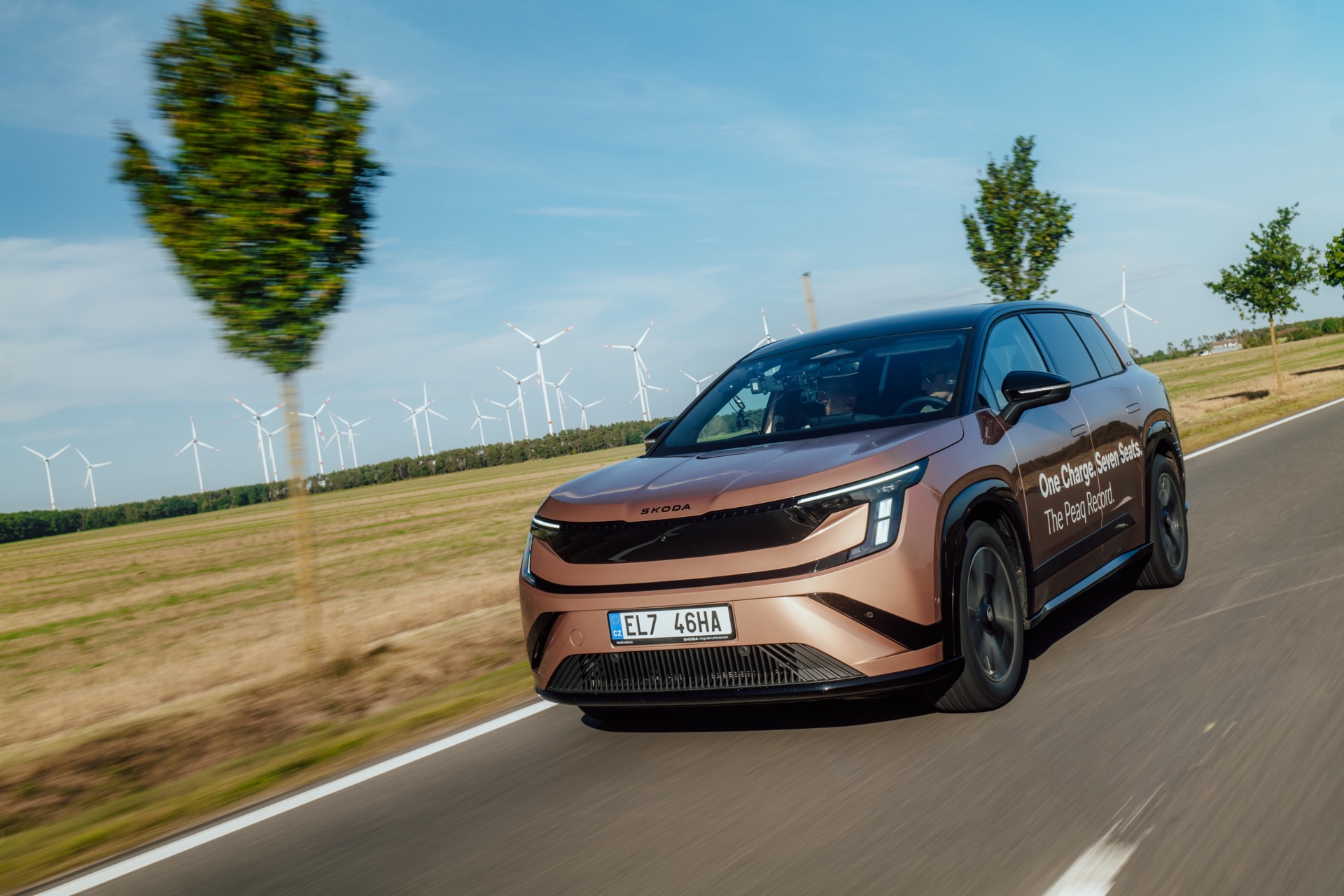 Škoda Enyaq iV fährt auf der Straße vor Windrädern in der Steiermark